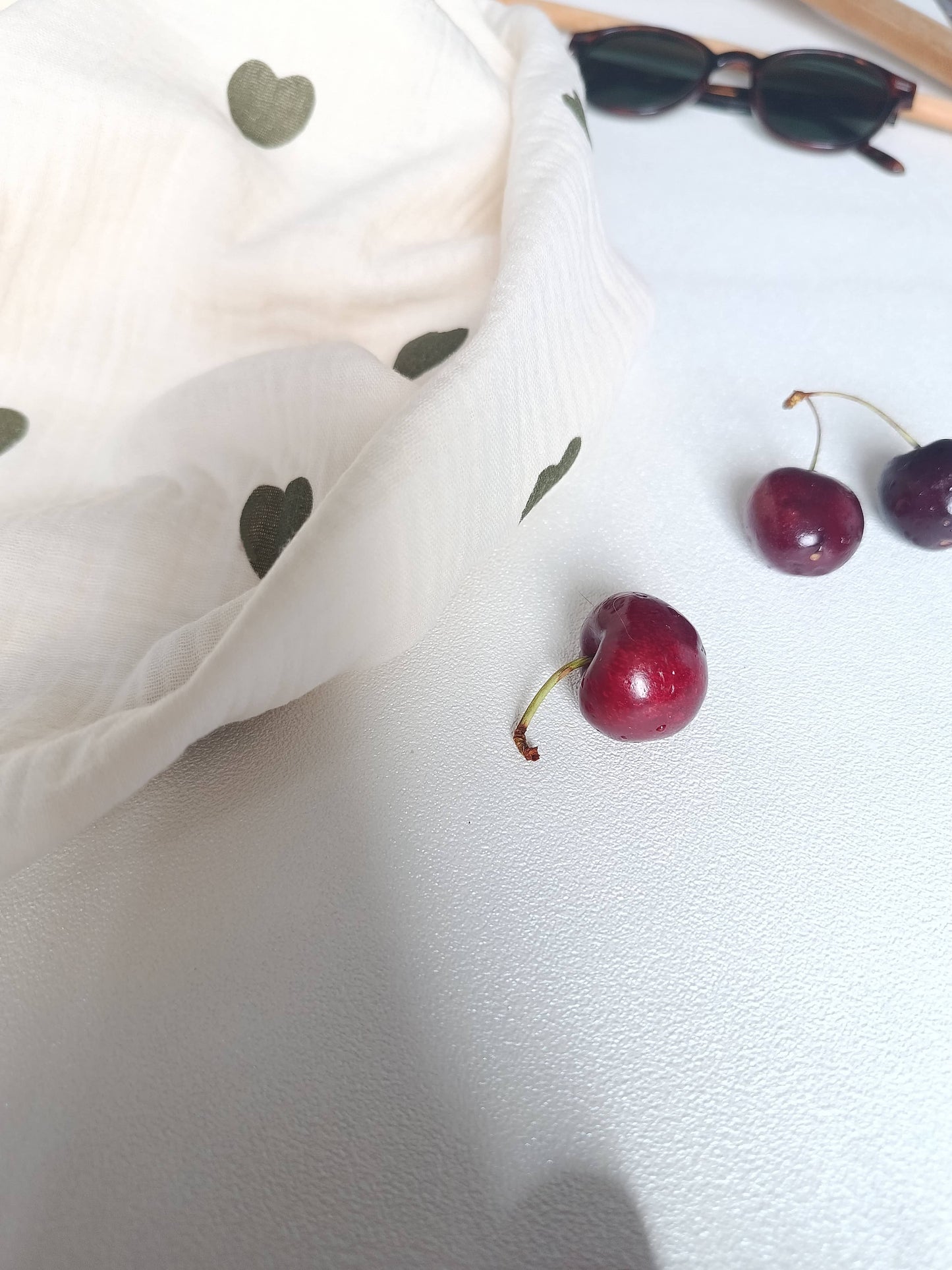 Foulard blanc lin en coton Bio imprimé cœur vert accompagné de cerises sur la photo