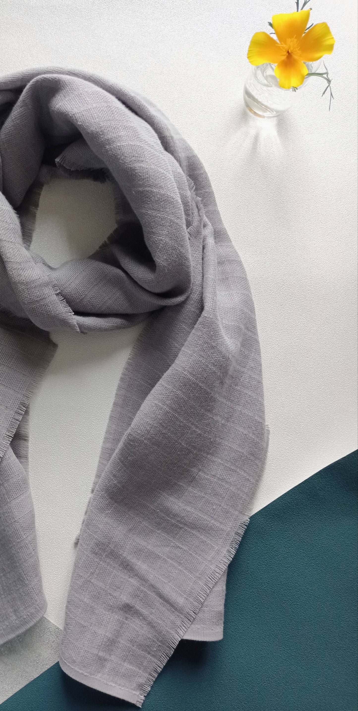 Foulard gris sur fond bleu avec une fleur jaune en décoration