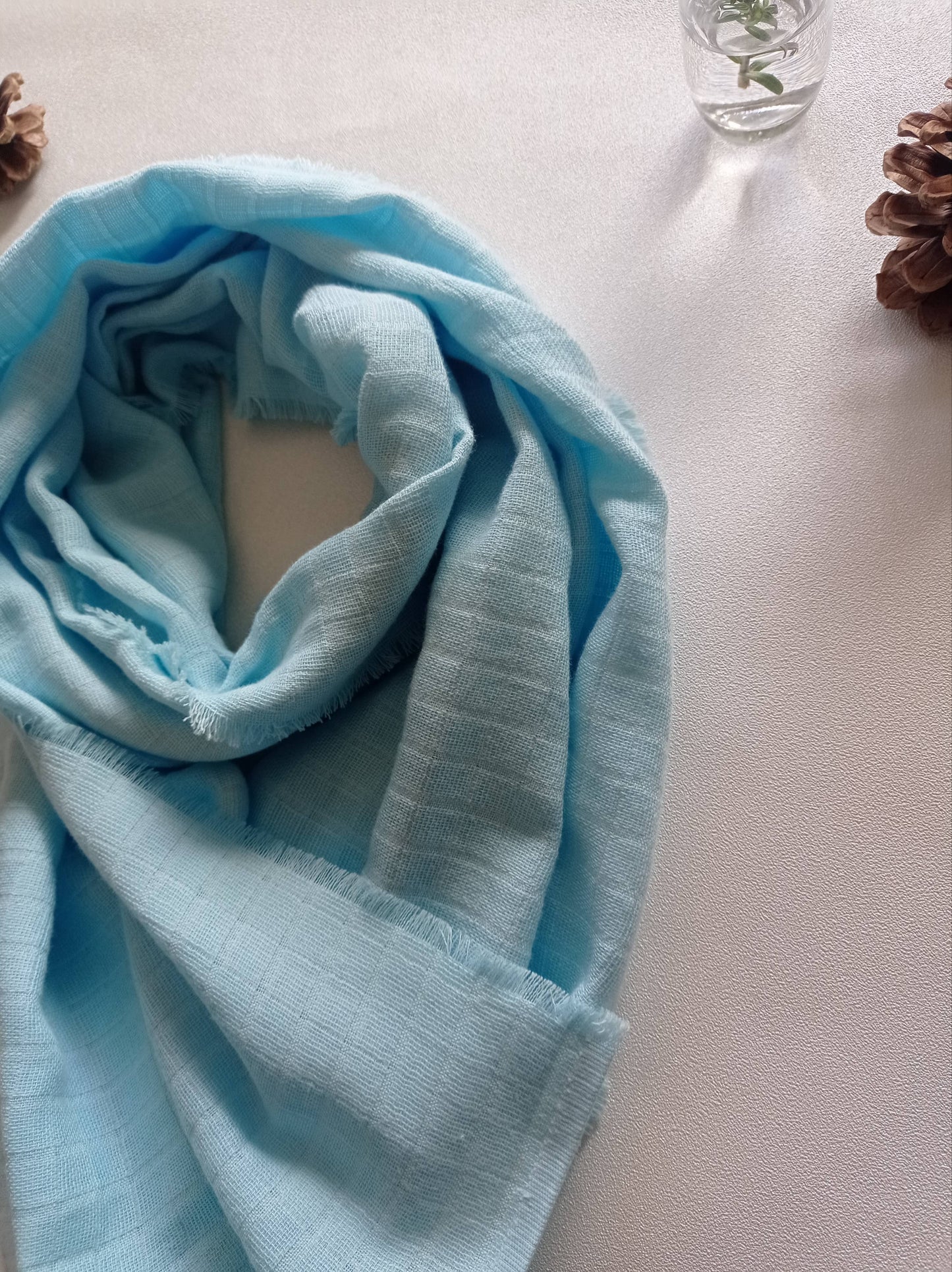 Echarpe bleu ciel en lumière sur fond blanc