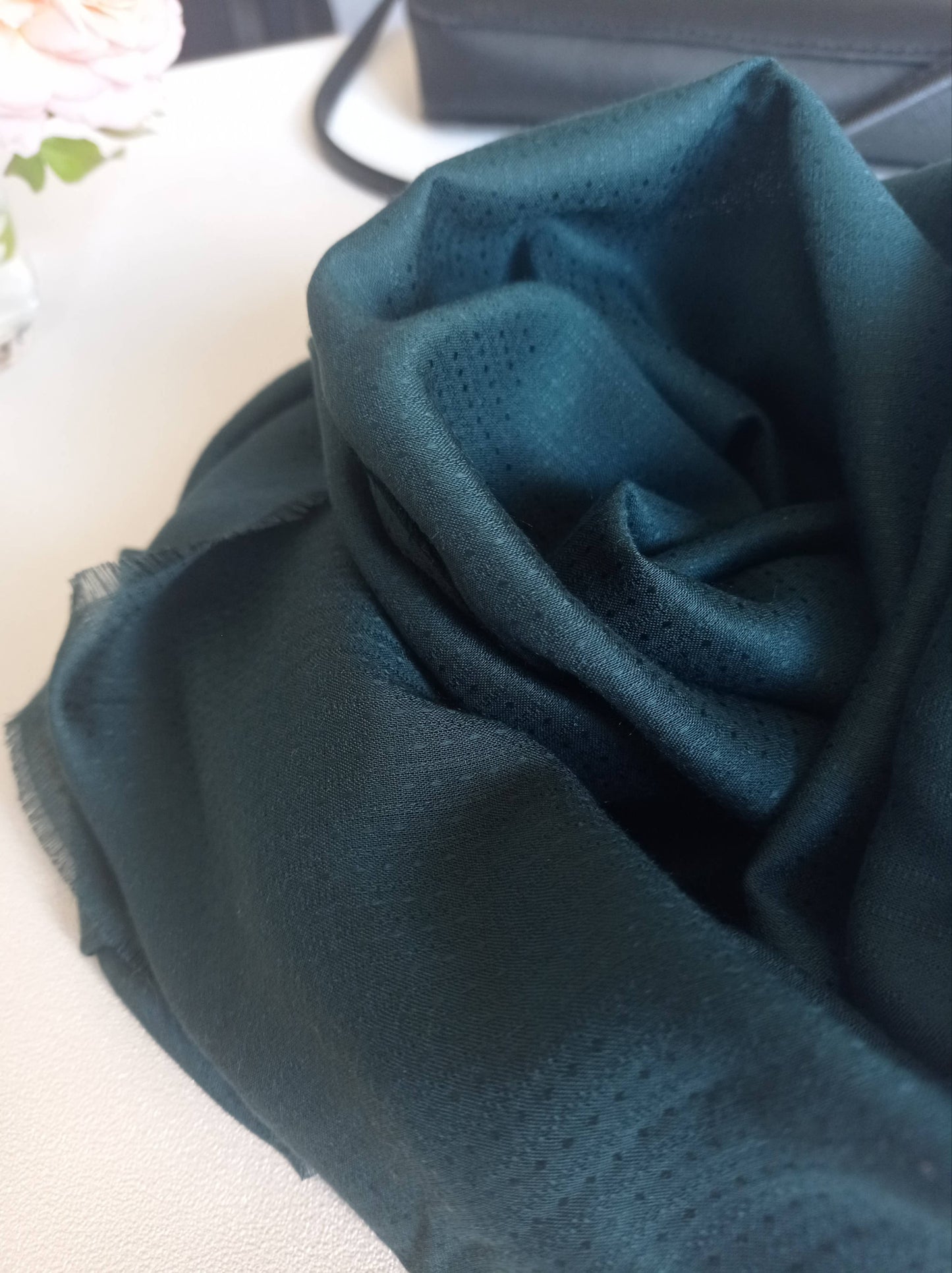 zoom sur un foulard soyeux vert aux bords à franges